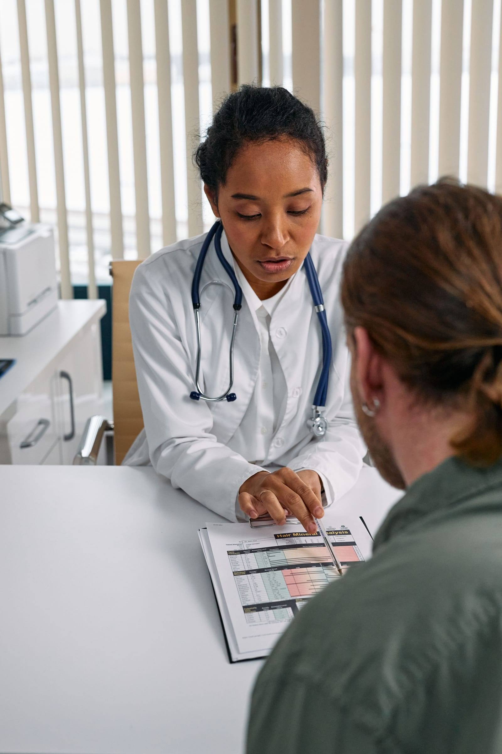 Ärztin bespricht mit einem Patienten am Schreibtisch einen Befund