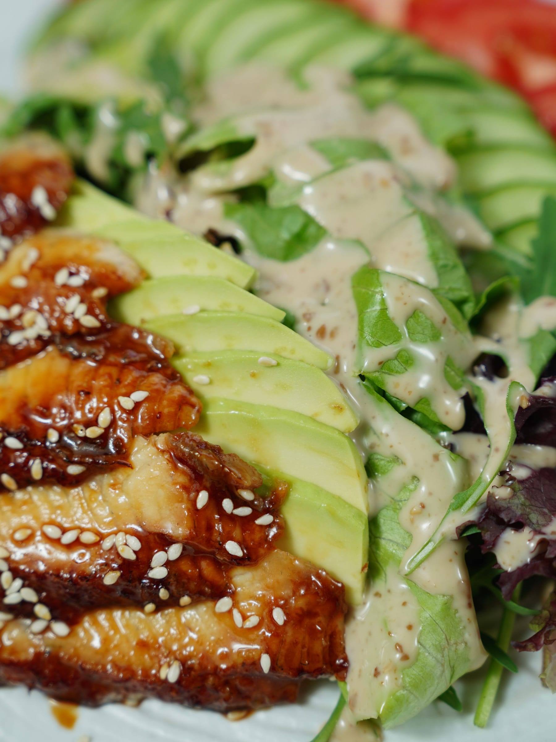 Salat mit Avocado, Hähnchen, Sesam und cremigem Dressing in Nahaufnahme